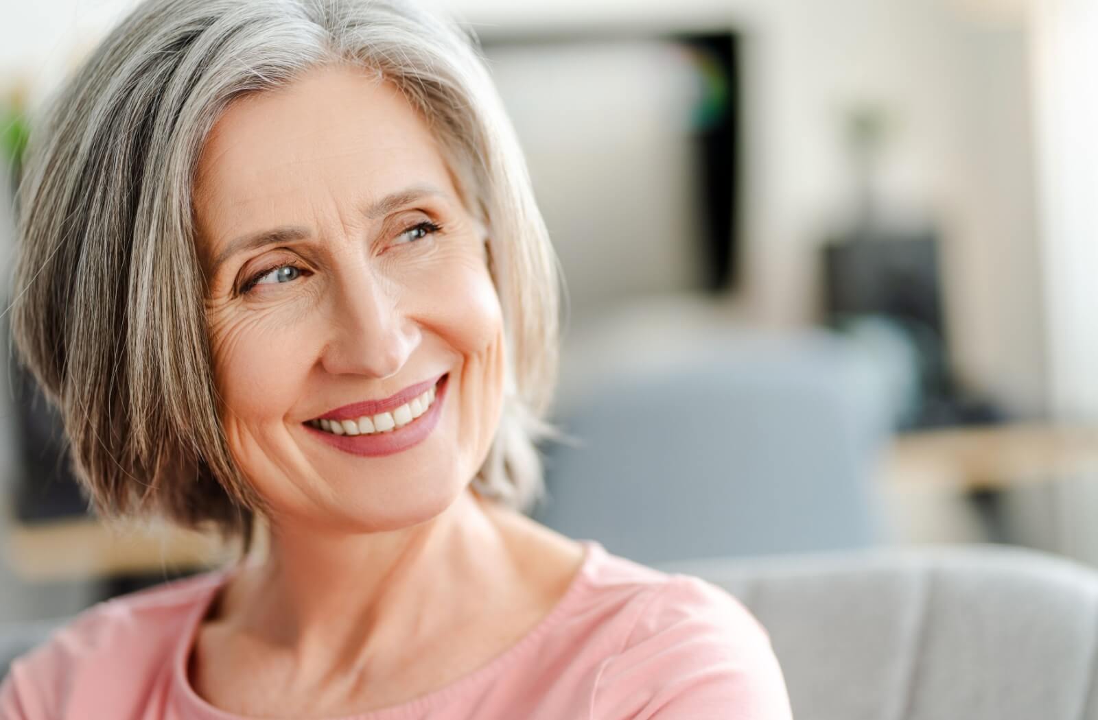 An older person smiles, happy with the longevity of their dental implants.