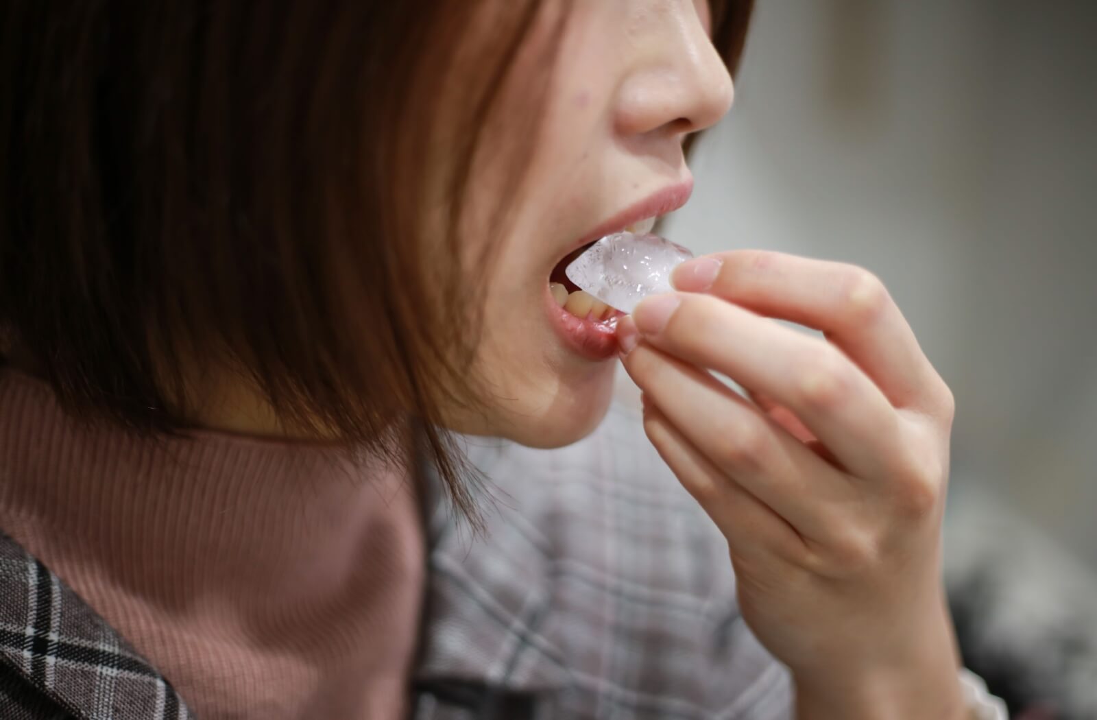 A person bites down on ice, risking their dental implant crowns breaking as they do.