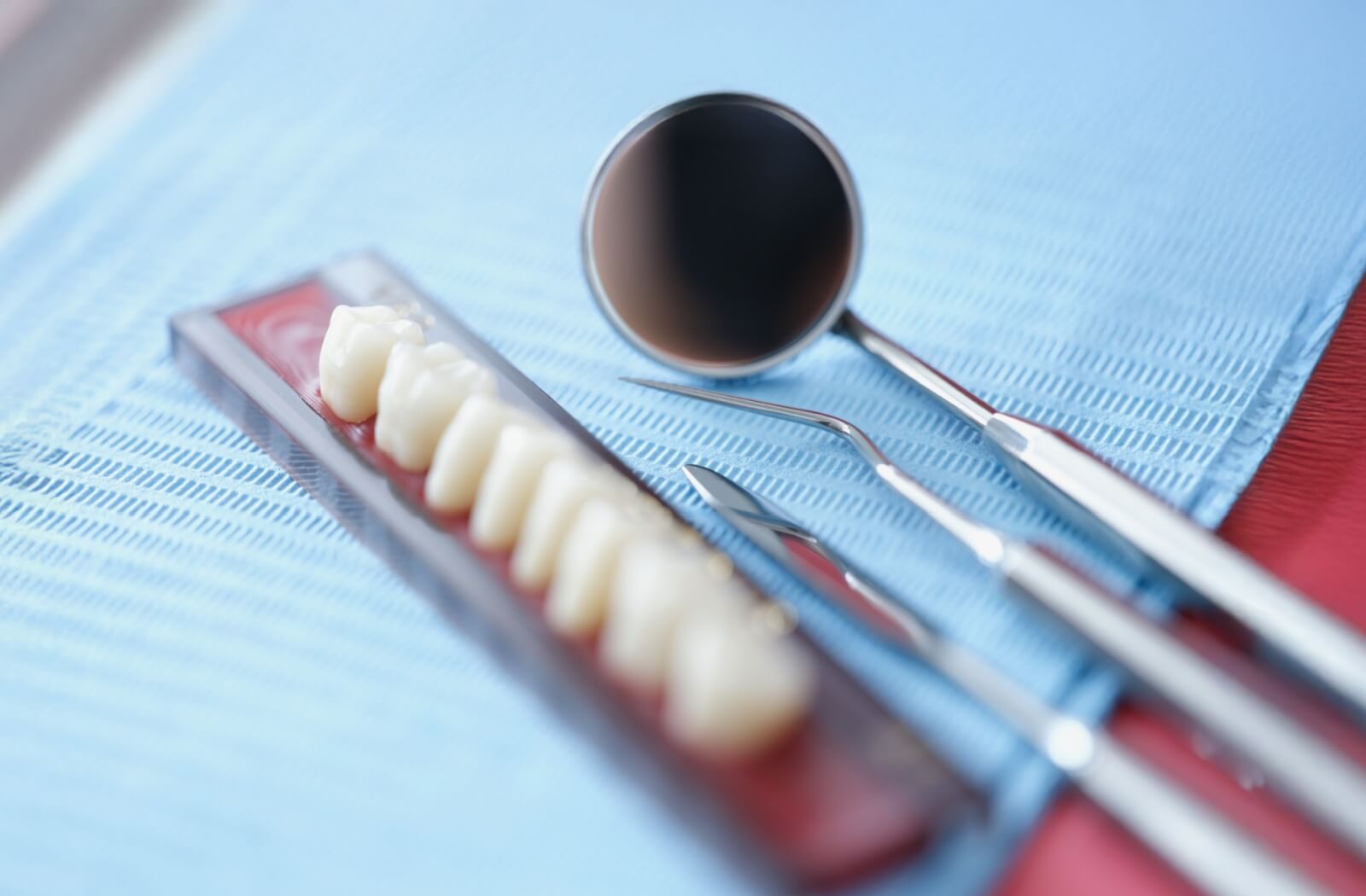 A set of dental tools and porcelain teeth on a tray in a clinical setting emphasizing professional dental care and prosthetics