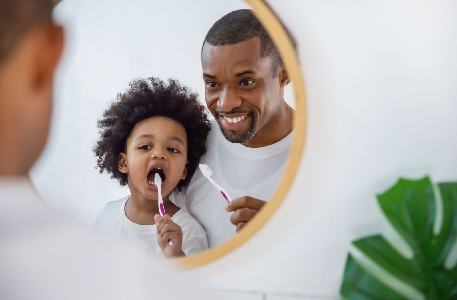 A father and his child brush their teeth together