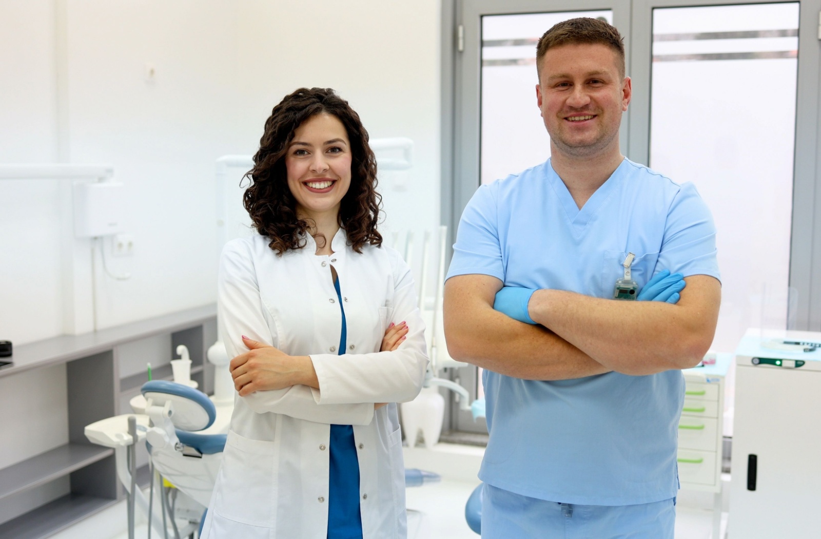 Two smiling dental professionals standing confidently in a bright modern clinic environment
