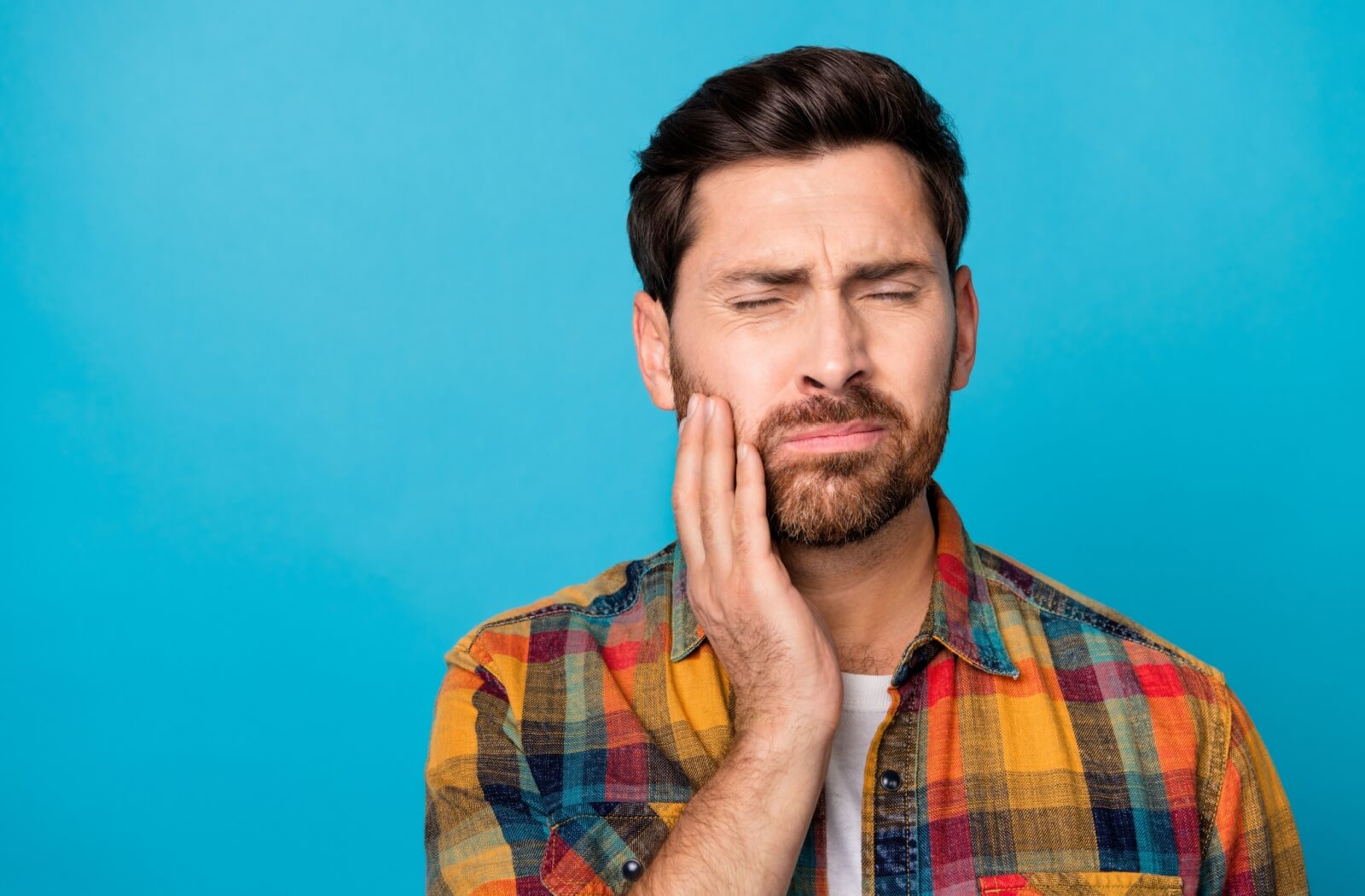 A person caressing their jaw in response to tooth pain.
